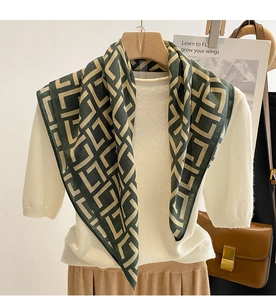 Detail of dark green and beige geometric silk scarf on a hanger with autumn outfit