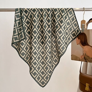 Elegant green and beige geometric silk scarf for women hanging on a stylish metal stand