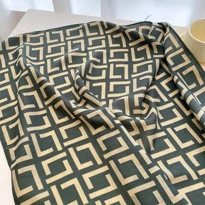 Detail of interlocking geometric pattern on dark green and cream twill scarf fabric
