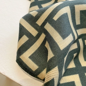 Close-up of interlocking geometric pattern on a thick green and beige twill scarf