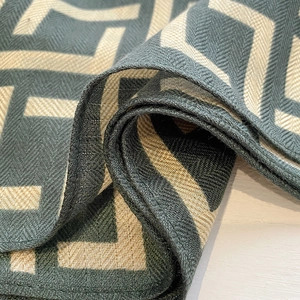 Close-up of green and beige geometric maze pattern silk scarf with herringbone texture