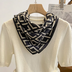 Elegant geometric black and beige silk scarf styled on a white knit sweater outfit