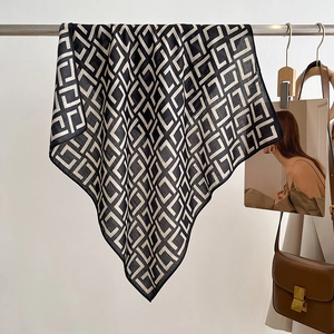 Minimalist black and white geometric diamond pattern square scarf draped on a metal rack