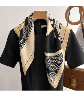 Close-up of silk square scarf featuring black base with beige spiral cloud patterns