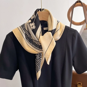 Elegant geometric floral silk scarf in black and beige draped on a wooden hanger