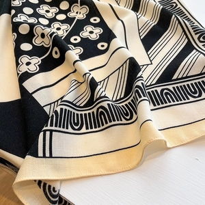 Close-up of black and white printed scarf with elegant herringbone weave and floral pattern