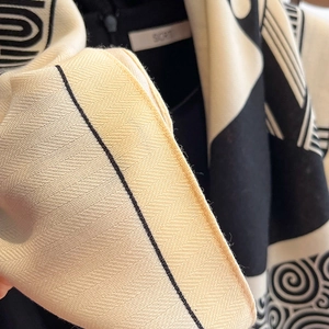 Macro view of herringbone texture and geometric print on silk scarf edge