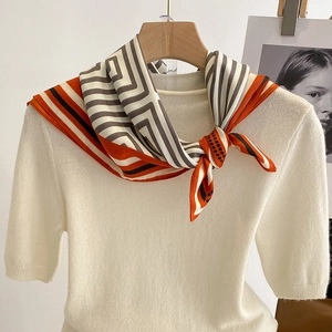 Geometric satin silk scarf for women featuring orange and grey patterns on a white sweater