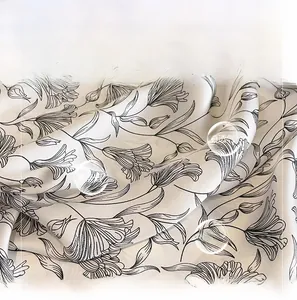 Detail aus seidigem Stoff mit eleganten schwarzen Blumendrucken auf weißem Hintergrund