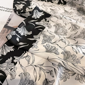 Detailaufnahme von Seidenschal mit elegantem schwarz-weißem floralem Lilienmuster