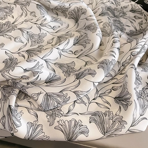 Detailansicht eines Seidenschals mit eleganten schwarzen Tintenblumenmustern auf Weiß