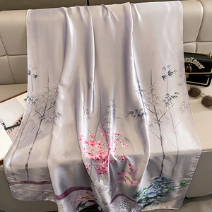 Elegant lavender silk scarf with bamboo and floral prints styled on a luxury leather sofa