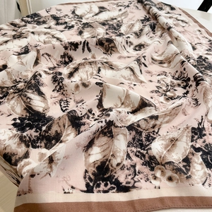 Detail of pink silk scarf with black floral prints and soft fabric texture stack