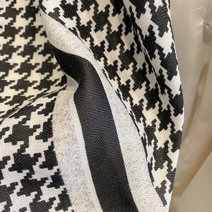 Detailed view of soft houndstooth pattern fabric with elegant woven texture and fringe