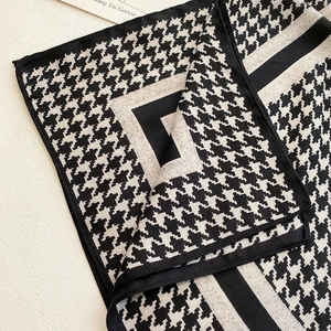 Detailed close-up of a houndstooth silk scarf with geometric patterns and smooth texture