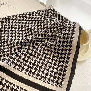Detail of a chic houndstooth scarf draped over a coffee cup with clear knit texture