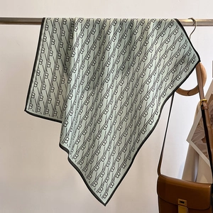 Close-up of light green silk scarf with black geometric pattern hanging on a metal bar