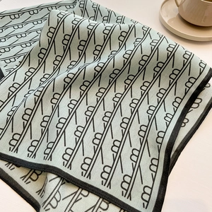 Detailed twill weave of mint green silk scarf with black letter print and coffee cup décor