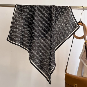 Detail of black and white square scarf with letter print on a minimalist metal rack