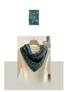Detail view of dark green cotton linen scarf with white embroidered leaf patterns