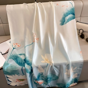 Elegant lotus print silk scarf in blue and pink draped on a stylish sofa for autumn