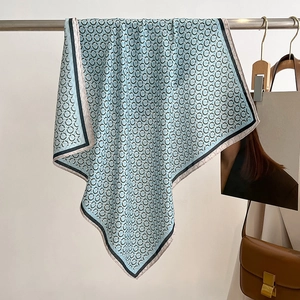 Detail of light blue silk scarf with black ring pattern draped on a metal rack