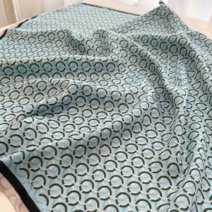 Macro shot of light blue silk scarf with dark green interlocking ring pattern details