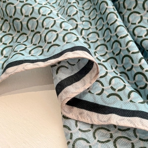 Detailed close-up showing the blue square silk scarf with green chain link patterns