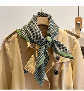 Detail of green and black houndstooth silk scarf styled on a khaki trench coat collar