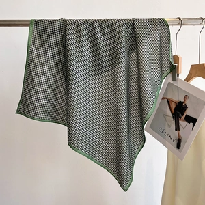 Classic green houndstooth scarf made of soft fabric hanging on a metal rack