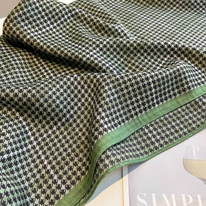 Close-up of green and black houndstooth scarf with fine knit texture and edge detail