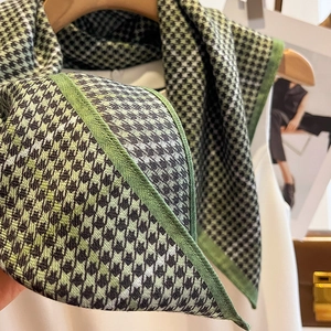 Detail of green houndstooth knitted scarf showing fine texture and dense stitched edges