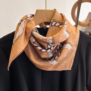 Elegant gold chain pattern silk square scarf displayed on a wooden hanger with dress