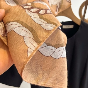 Detailed macro view of the chain pattern and twill weave texture on a brown silk scarf