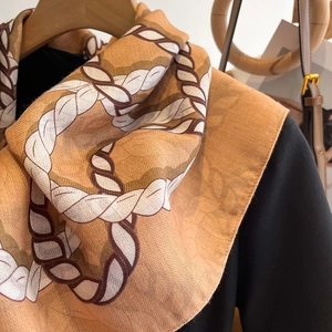 Detailed texture of camel silk scarf with chain pattern on a wooden hanger