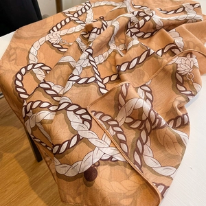 Close-up of orange silk scarf showing herringbone texture and white lotus floral pattern