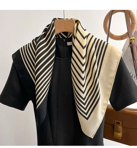 Detail showing elegant black and white geometric pattern scarf draped on a wooden hanger