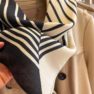 Detailed view of striped cotton scarf with herringbone weave and silky texture on a coat