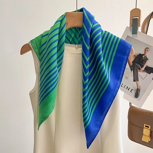 Detail of blue and green striped silk scarf on white dress with lightweight texture