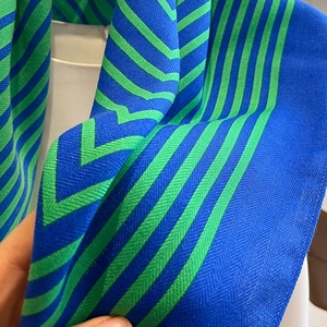 Detail of blue and green striped scarf fabric showing fine twill texture and soft drape