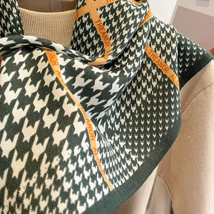 Détail d'une écharpe en maille pied-de-poule verte avec rayures orange et texture