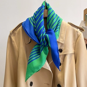 Close-up of blue and green striped scarf styled with a classic beige trench coat collar