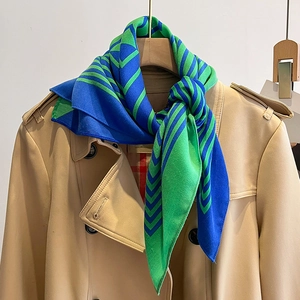 Detail of blue and green striped scarf with geometric V-pattern on a beige trench coat