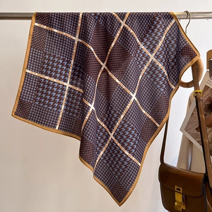 Détail d'un foulard en soie à motif pied-de-poule suspendu sur un support métal