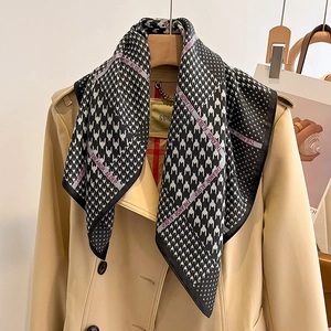 Détail de l'écharpe pied-de-poule avec logo nouée sur un trench-coat beige classique