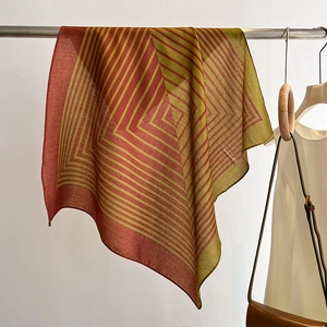 Detail of striped geometric square scarf draped on a metal rack with lifestyle outfit