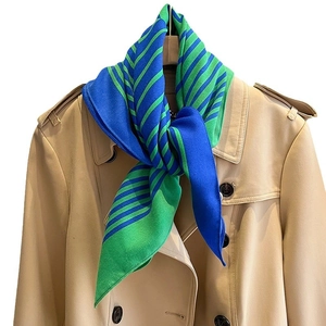 Minimalist striped scarf in blue and green cotton feel, styled on a khaki trench coat