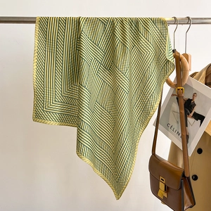 Detailansicht des gelb-grünen gestreiften Seidentuchs mit Handtasche und Trenchcoat-Styling