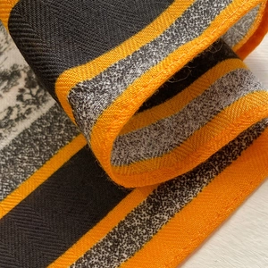 Detail eines quadratischen Seidenschals mit hochwertigem Köpergewebe in Schwarz, Grau und Orange