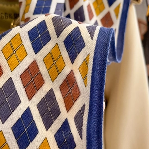 Macro view of geometric diamond pattern fabric texture with blue woven edge and metal logo